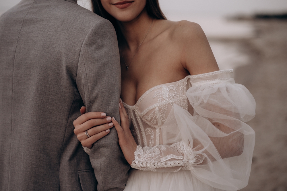 Close,Up,Of,Bride,With,Ring,Hugging,Groom,At,Beach,